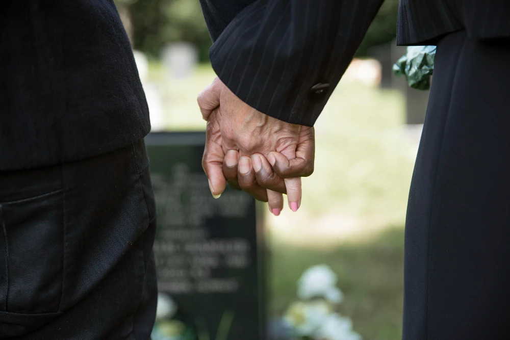 mensen houden elkaar de hand tijdens een begrafenis